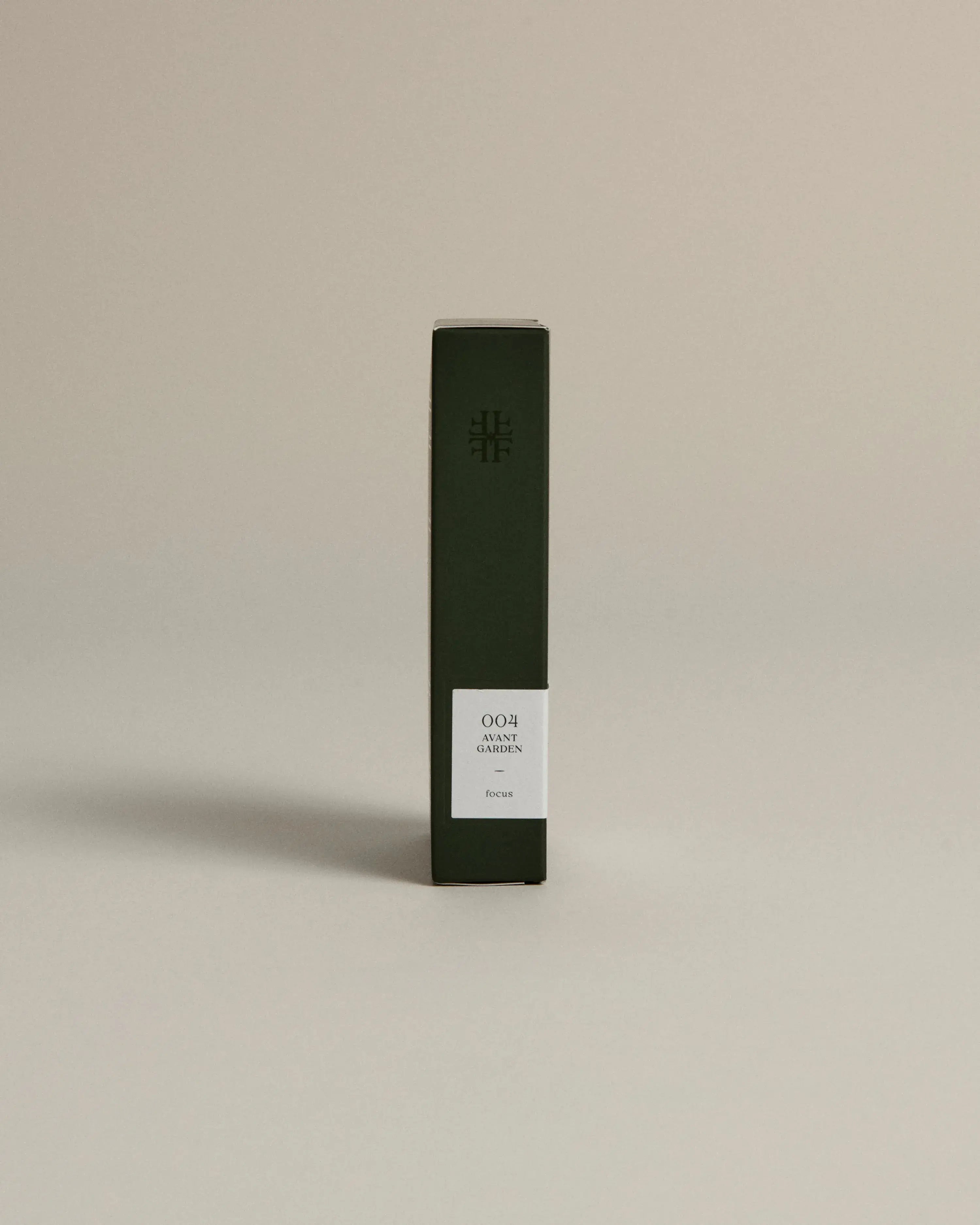 Minimalist dark green box labeled ‘004 Avant Garden – Focus’ by FORGRAVE, standing upright on a beige background.