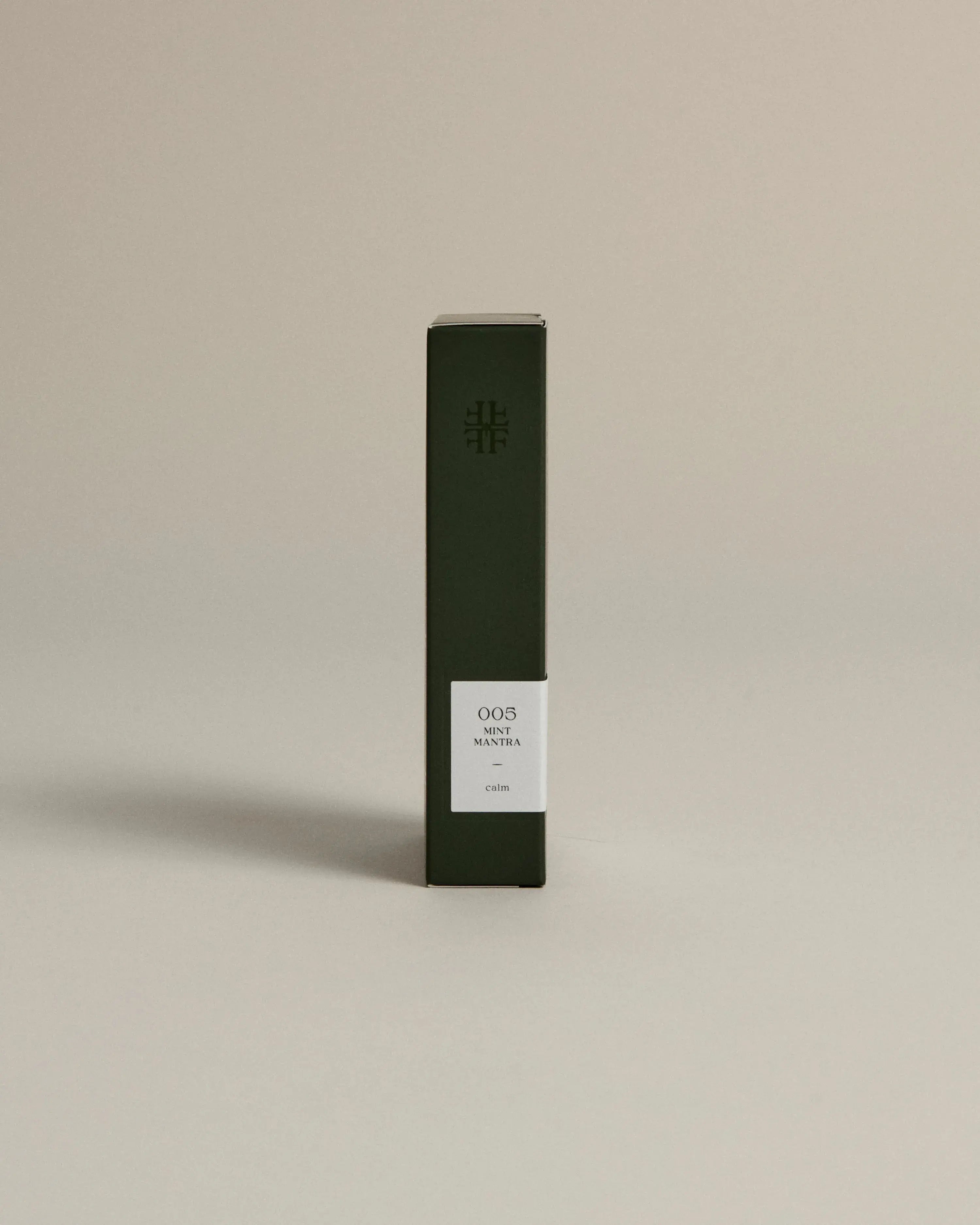 Minimalist dark green box labeled ‘005 Mint Mantra – Calm’ by FORGRAVE, standing upright on a beige background.