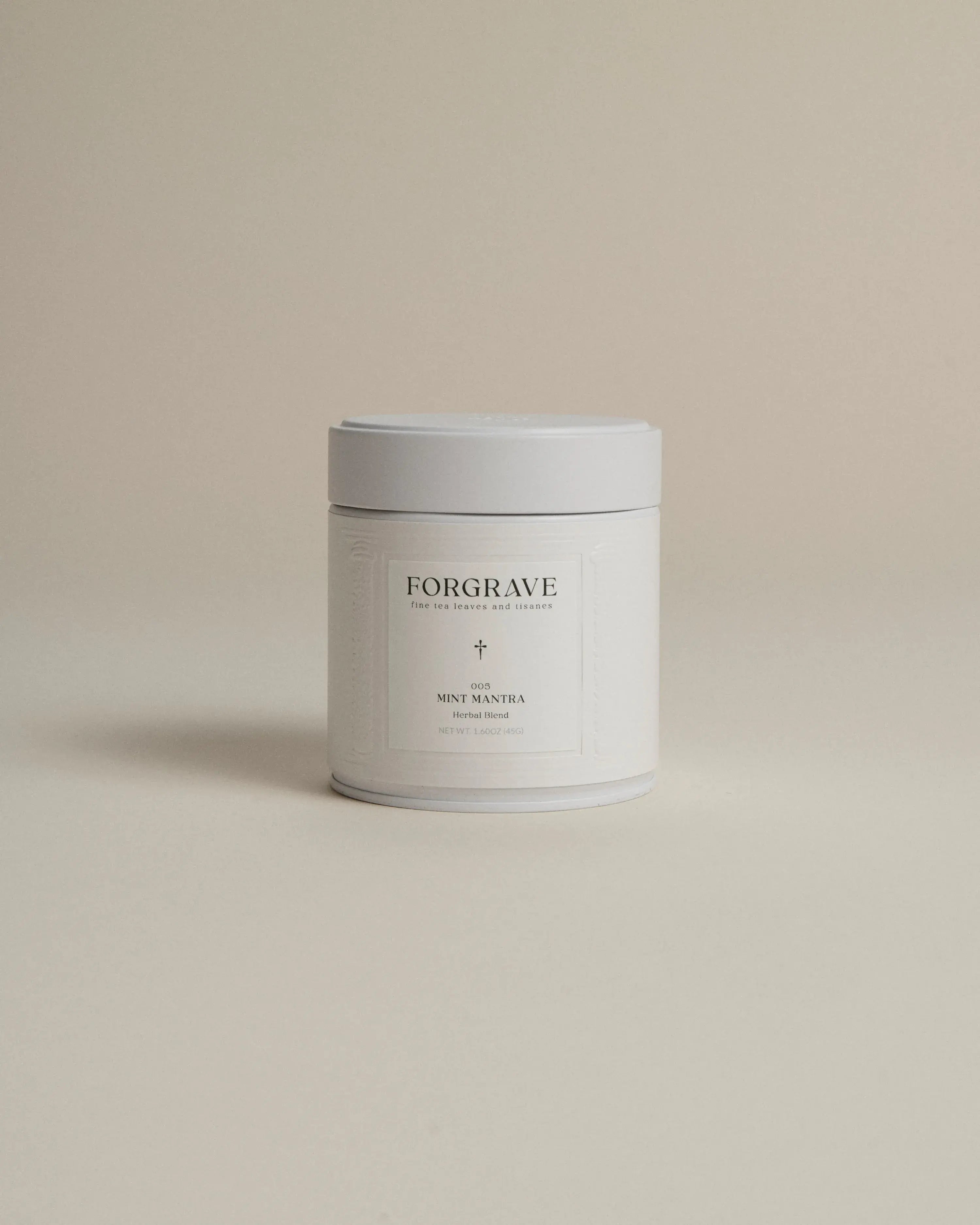 White tea canister labeled ‘005 Mint Mantra Herbal Blend’ on a beige background.