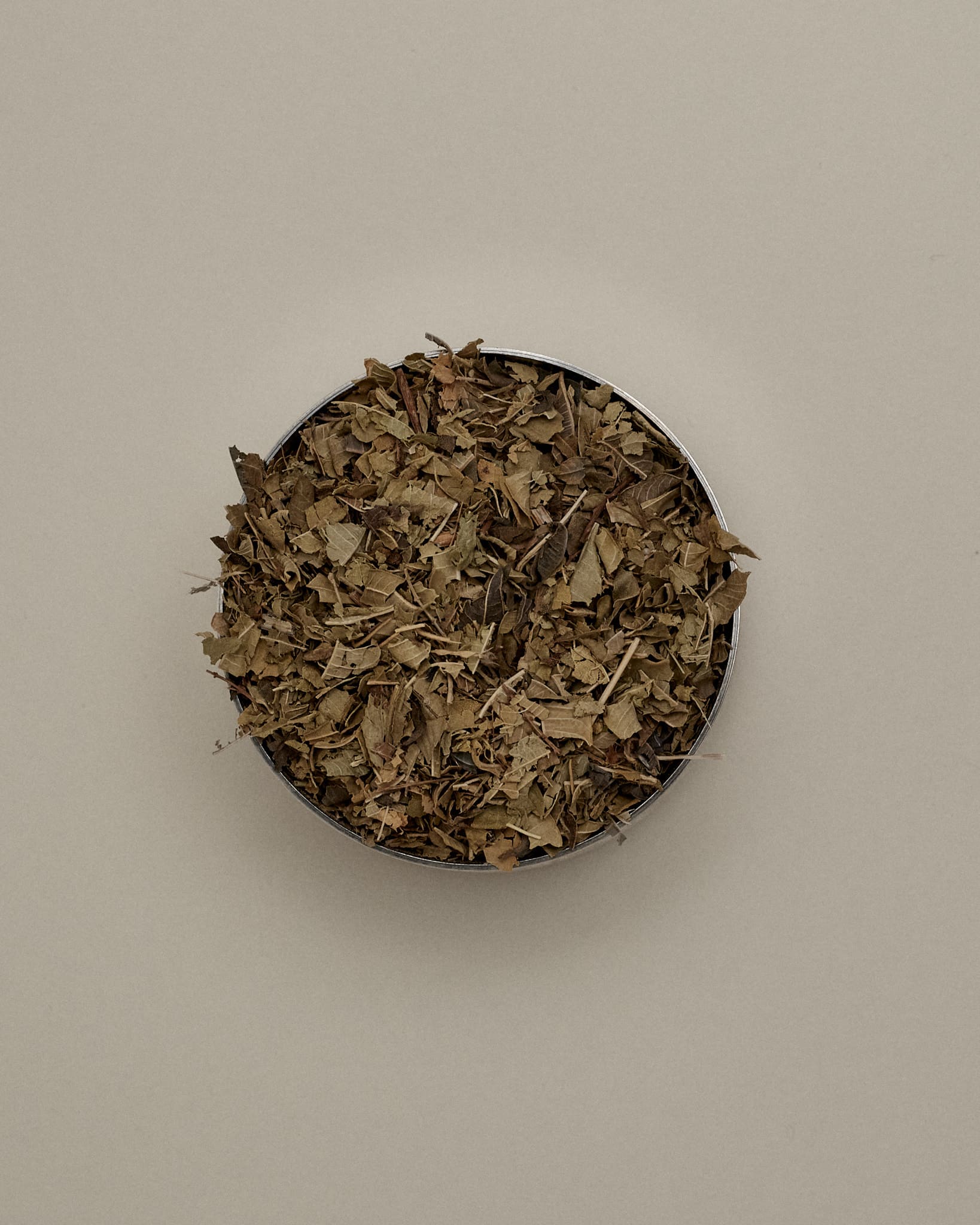 Open Forgrave Augusta Medium Caddy viewed from above, filled with organic loose leaf tea — dried whole leaves and stems in a refillable tin